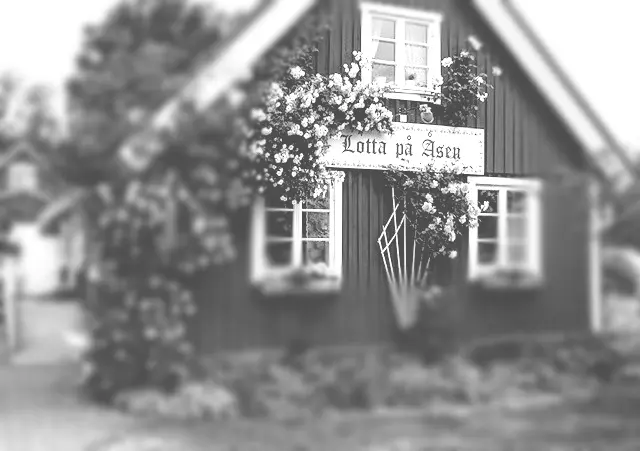 Svartvit bild av caféhuset med skylten Lotta på Åsen och klätterrosor