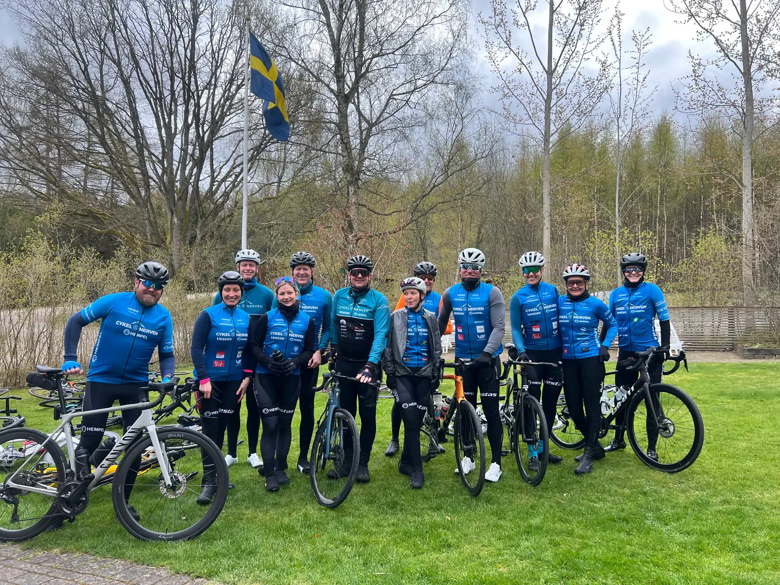 Cyklister i blå tröjor med sina cyklar i trädgården