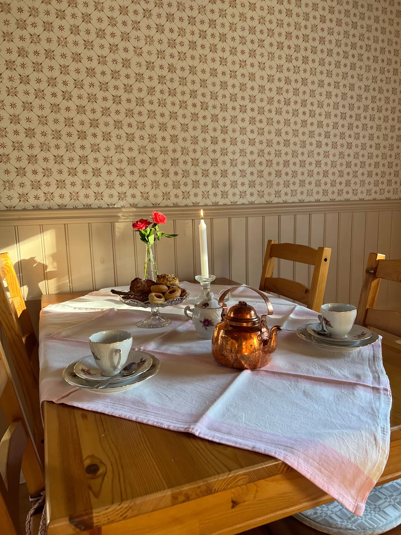 Dukat bord inne i caféet med kopparkanna, kaffekoppar och tända ljus