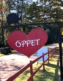 Röd hjärtformad skylt med texten Öppet vid infarten
