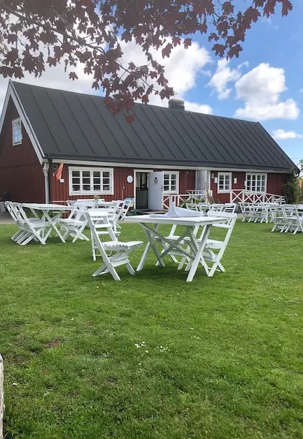 Trädgård och cafébyggnad, med vita bord på gräsmattan