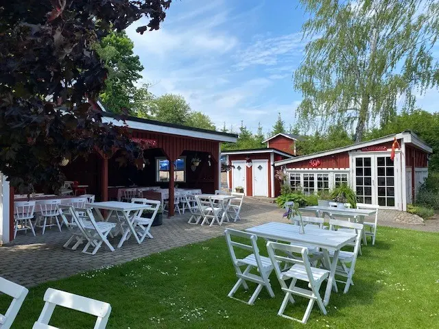 Trädgården med vita bord och stolar framför de röda caféhusen