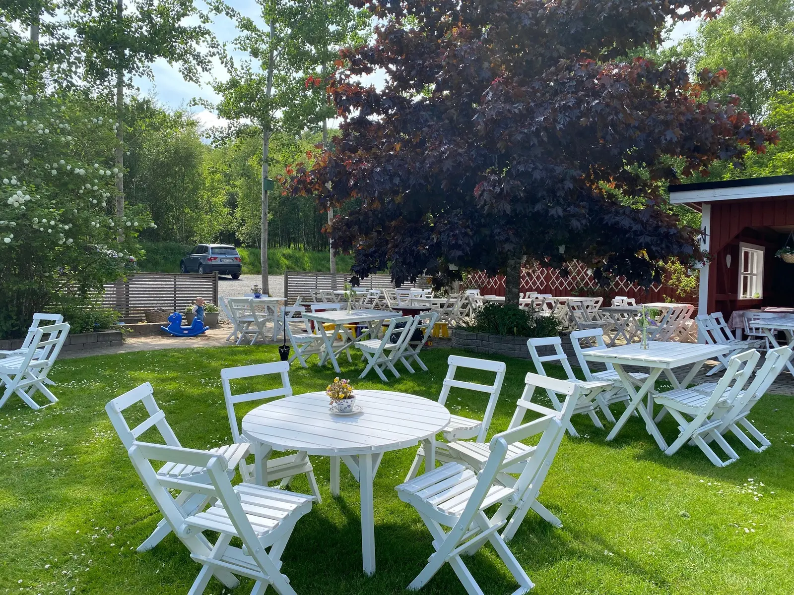 Trädgården med vita bord och stolar på gräsmattan