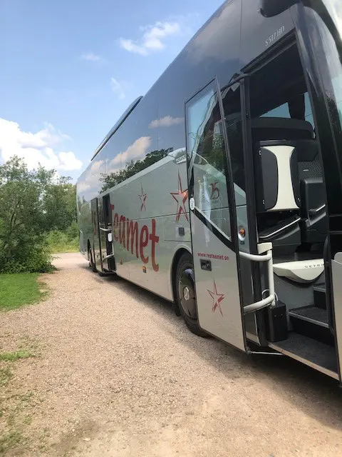 Turistbuss med öppen dörr vid caféet